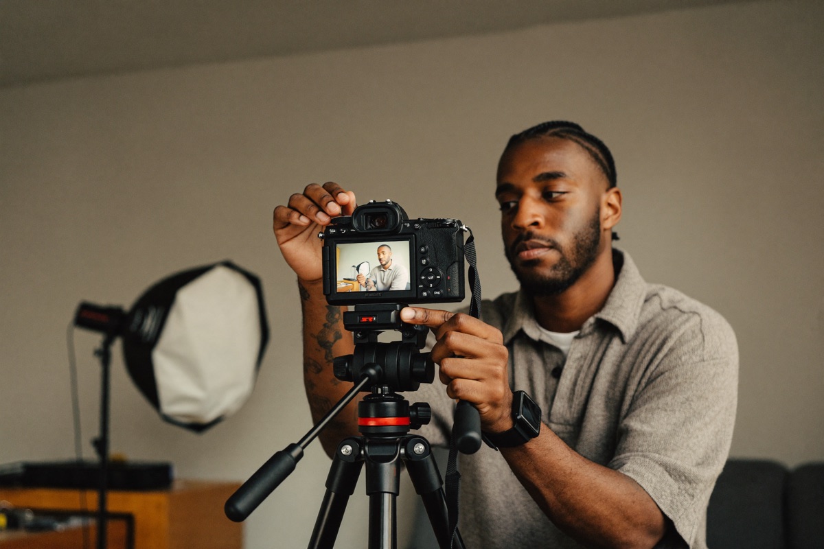 A content creator filming with a camera on a tripod in a home studio