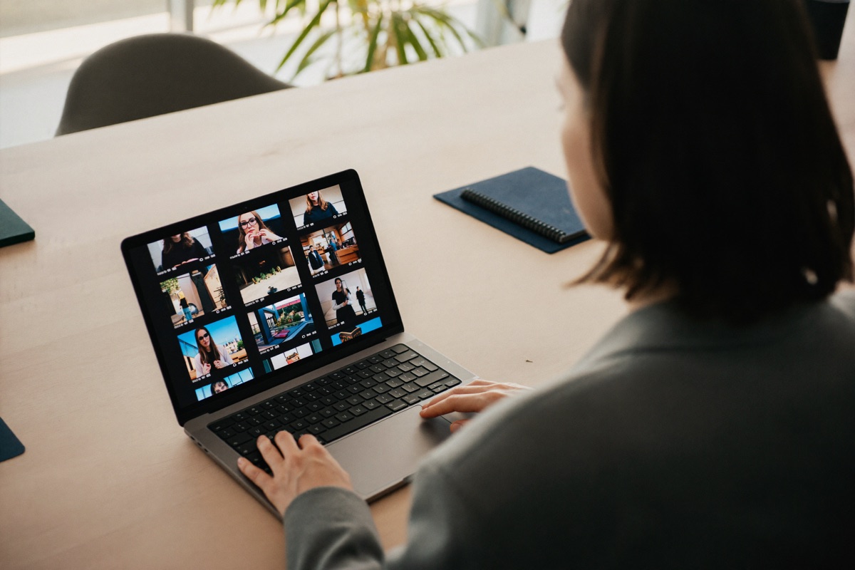 A professional reviewing a grid of video clips on a laptop