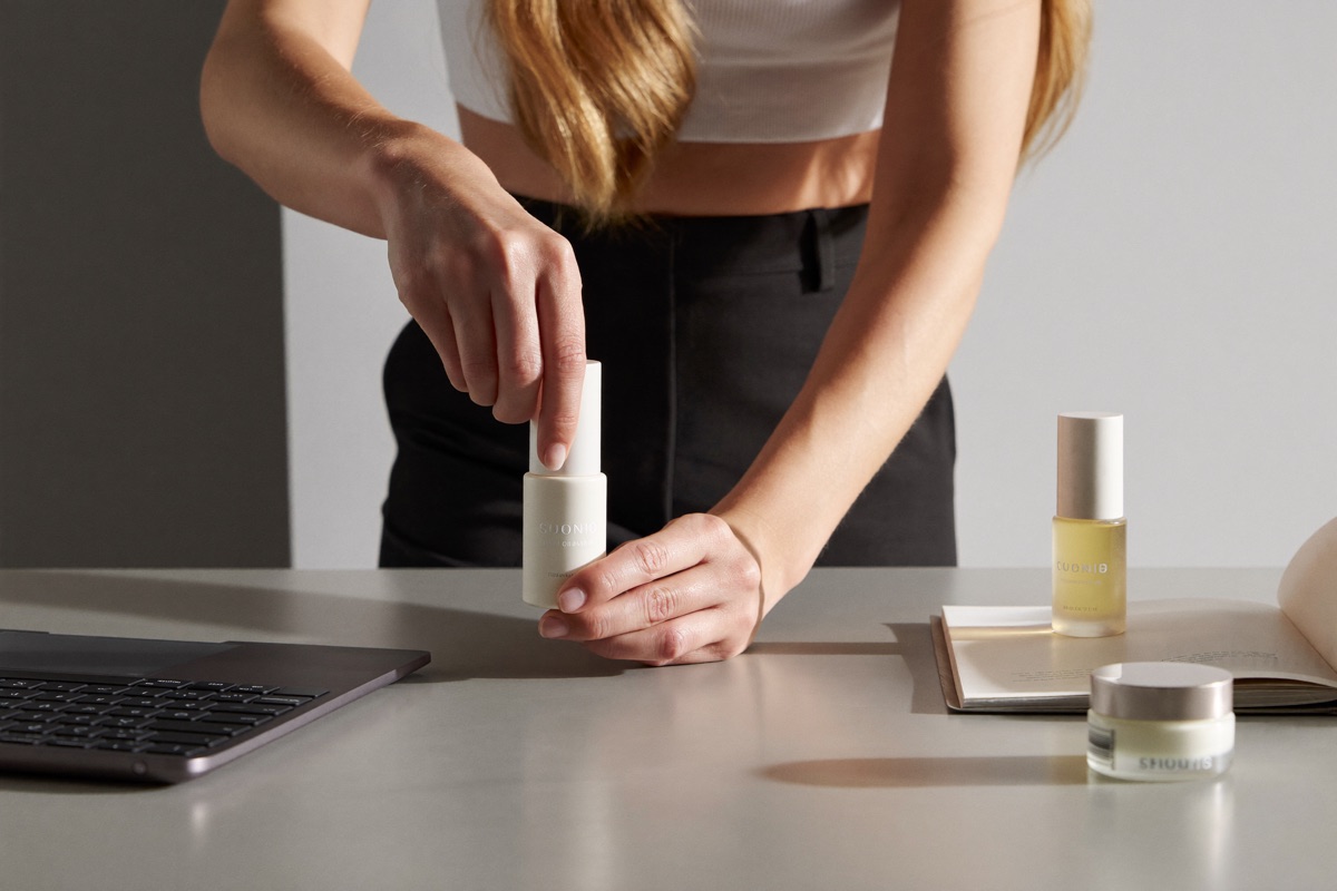 A stylist arranging a premium skincare product on a clean set