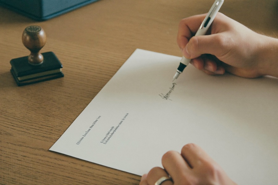 Hands signing an official document beside a notary stamp