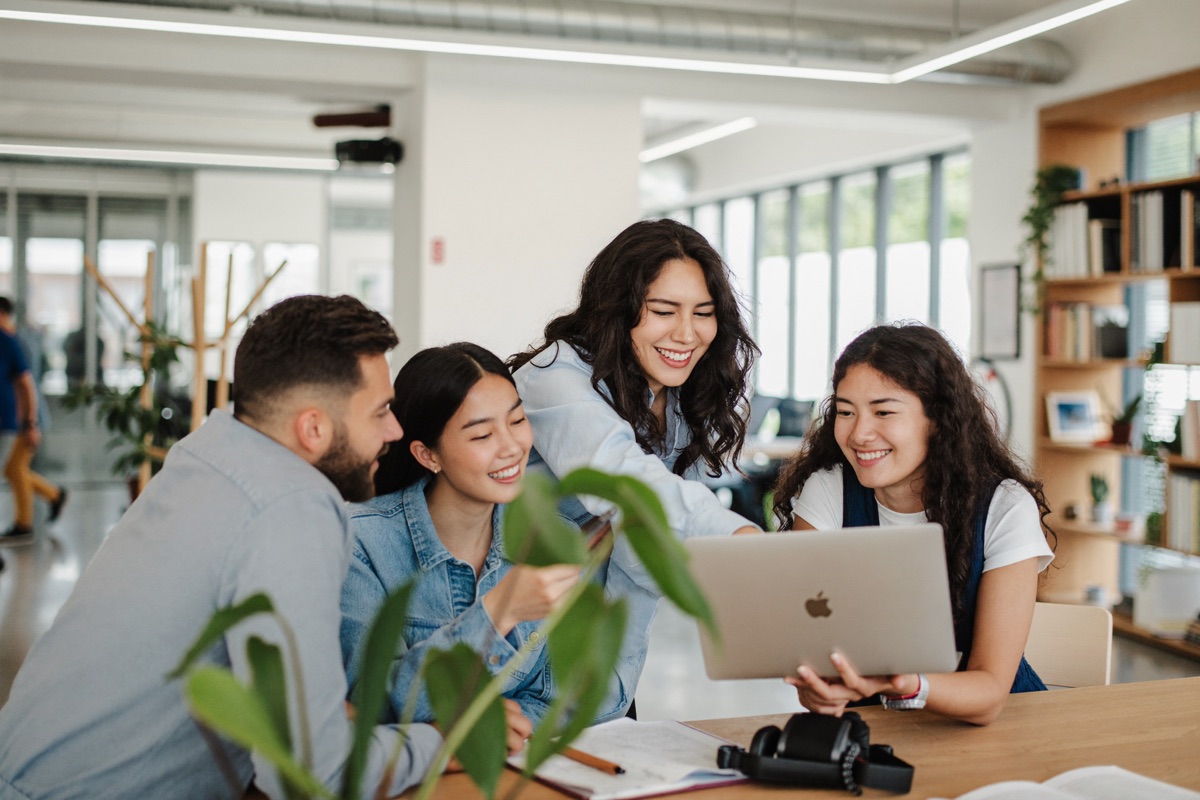 A marketing team collaborating around a laptop in a modern office